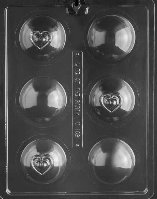 Picture of chocolate mold for making hot chocolate bombs or bath bombs. 6 sphere-shaped cavities on a mold with a small heart impression on the sphere.