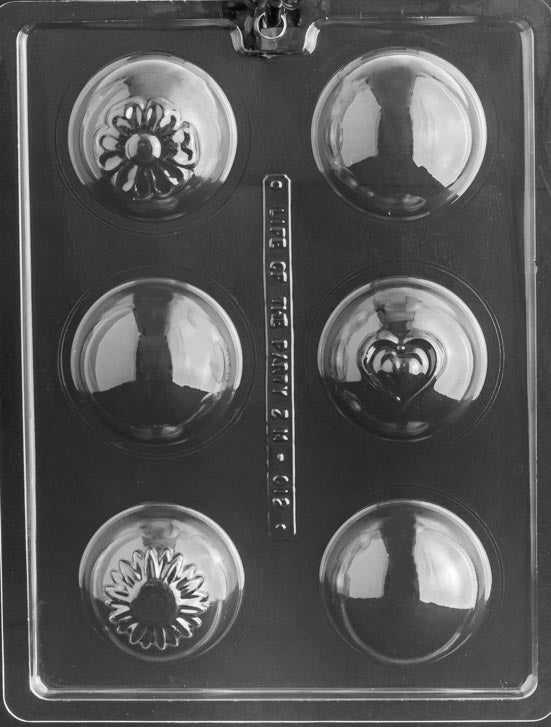 Picture of chocolate mold for making hot chocolate bombs or bath bombs. 6 sphere-shaped cavities on a mold with a small heart and small flower impressions on the sphere.